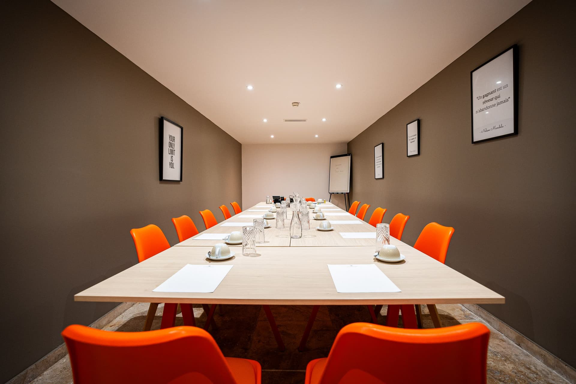 Salle de réunion avec chaises orange et tableaux motivants.